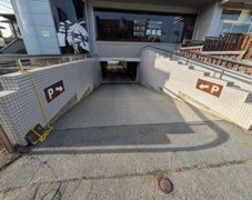 建物の下へスロープが伸びている地下駐車場入り口の写真
