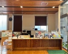 左側に観葉植物が置かれ、木製のカウンターには色々な種類の資料などが置かれている受付カウンターの写真