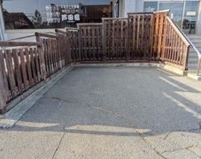 建物前にある木製のフェンスで仕切られている正面駐車場の写真