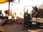トラックの荷台に積まれたストーブ用の薪を下ろす作業をしている様子の写真