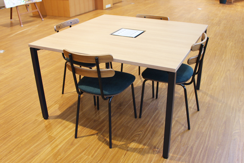 正方形のテーブルに、4脚の椅子が設置されている4人用デスクの写真