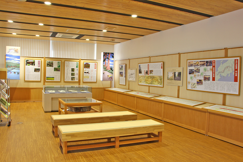 中央に2脚のベンチが置かれ、壁や、壁の側の棚には資料が展示されている史料展示スペースの写真