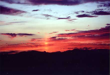 沈んでいく太陽で空がオレンジ色に染まっている幻想的な白樺高原の夕陽の写真