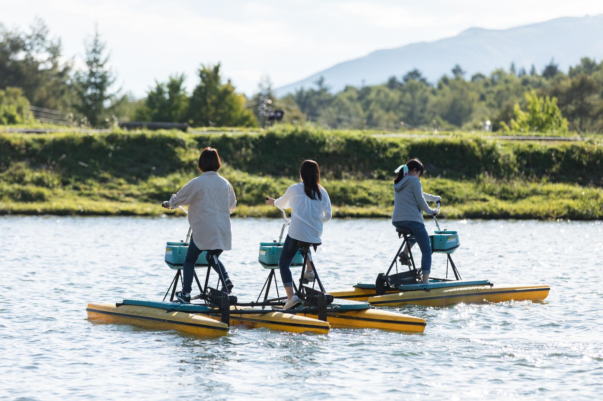 女神湖で自転車のような乗り物 ロボアメンボに乗って楽しんでいる3人の女性たちの写真
