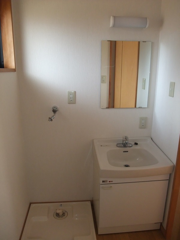 左側に洗濯機を置くスペース、右側に洗面台がある洗面所内の写真