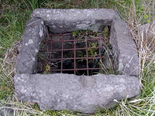 四角に石で囲まれ、井戸の入り口に柵が取り付けられている塩井の写真